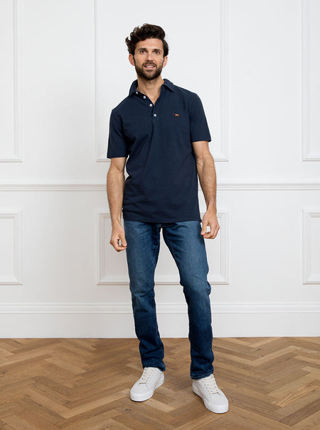 Man wearing navy blue polo shirt in 100% cotton with Newmarket 875 horse logo embroidered on the front.